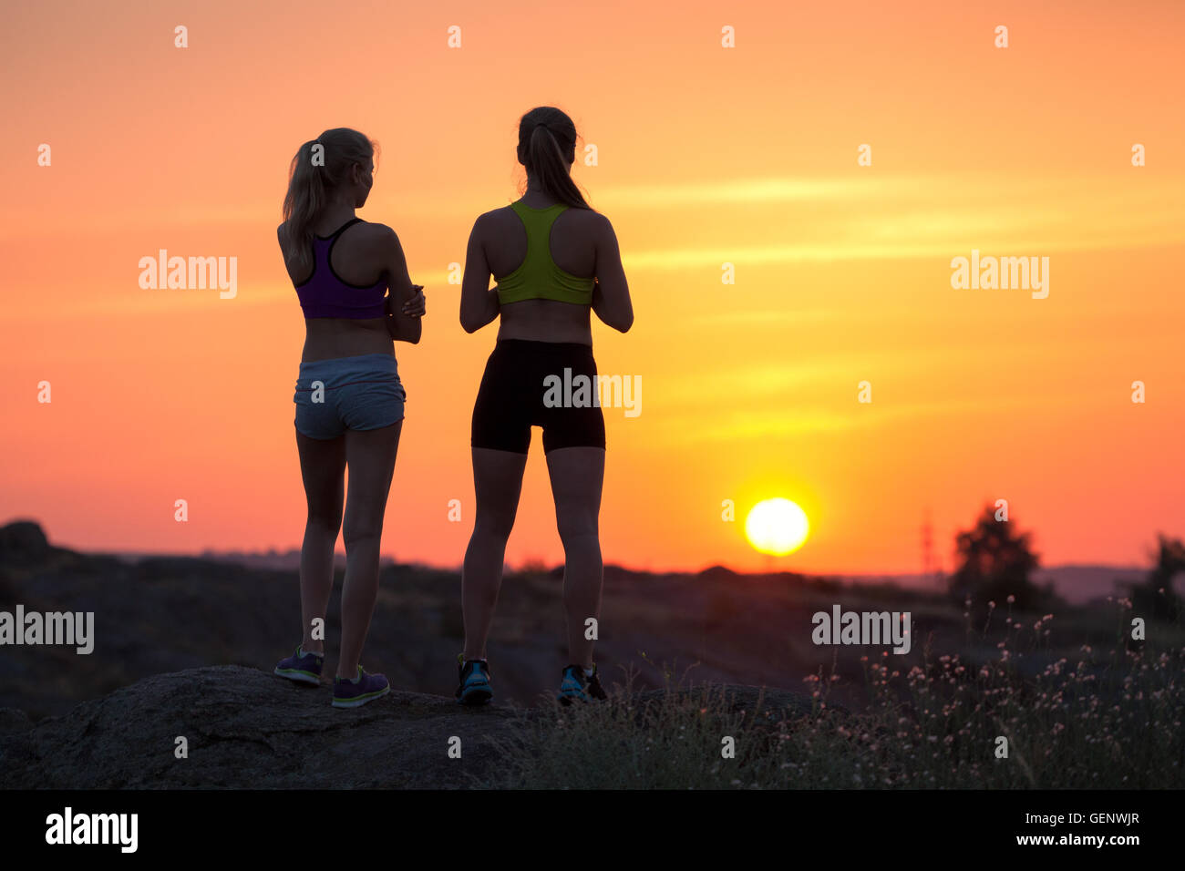 Bellissimo paesaggio con silhouette di giovani ragazze sportivo al tramonto sulla montagna in estate. Donne Fitness riposo dopo lo sport Foto Stock