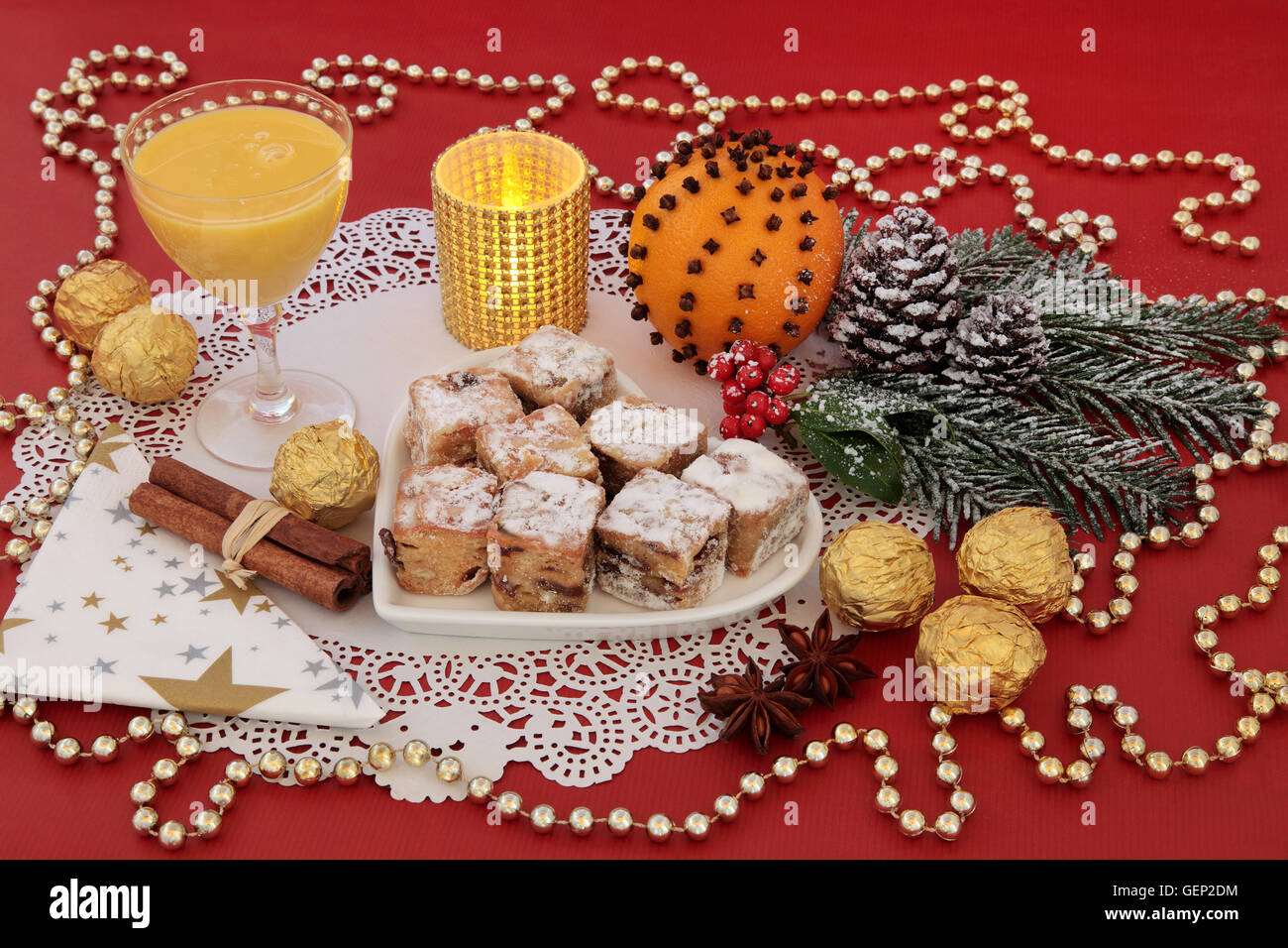 Dolce natalizio del cibo con lo Stollen dolci, uova nog, lamina di cioccolatini incartati, spezie, candela, arancione pomander e decorazioni su un Foto Stock