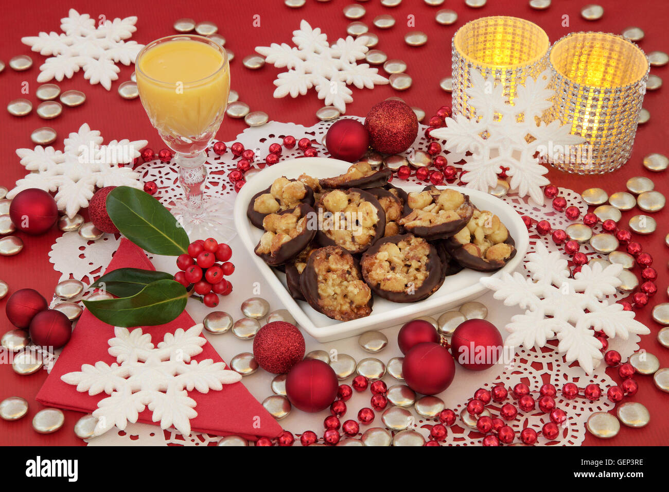 Scena di natale di biscotti Fiorentino su un cuore piastra sagomata, zabaione, agrifoglio, candele e ninnolo decorazioni con i fiocchi di neve. Foto Stock