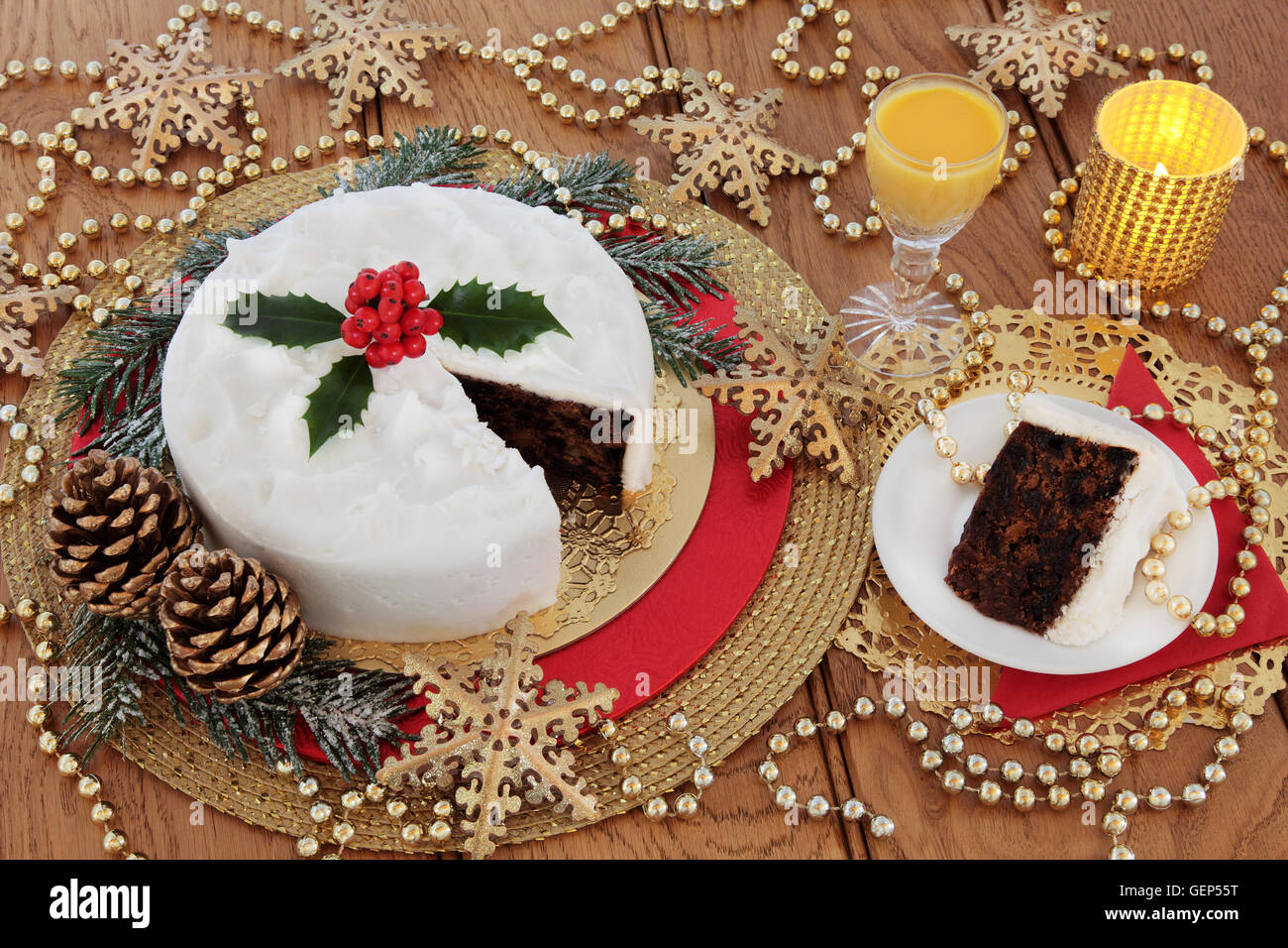 Torta di Natale e slice, con uovo nog, agrifoglio bacche, candele, oro ninnolo il simbolo del fiocco di neve decorazioni con trefoli di tallone. Foto Stock