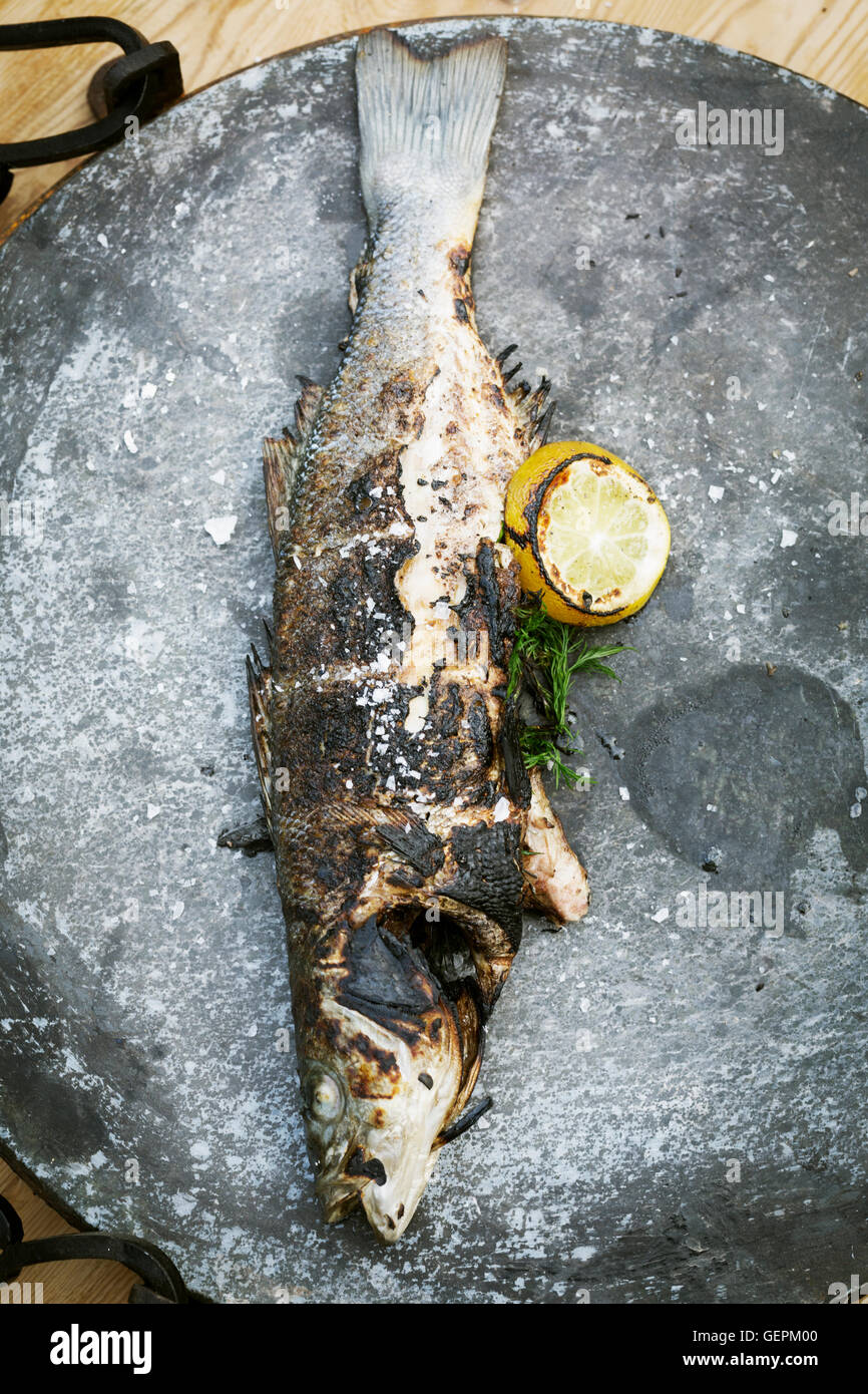 Elevato angolo di visione di un pesce alla griglia con limone e erbe aromatiche. Foto Stock
