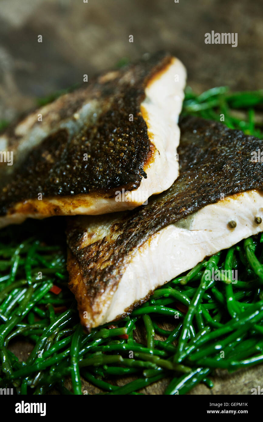 Close up di grigliate di pesce Filetti con pelle croccante su un letto di samphire. Foto Stock