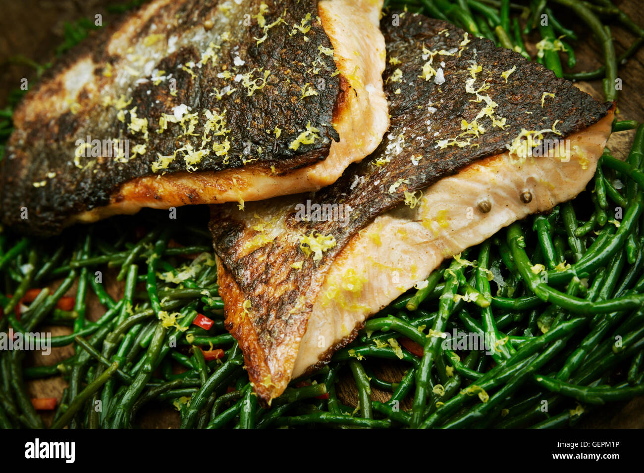 Close up di grigliate di pesce Filetti con pelle croccante su un letto di samphire. Foto Stock