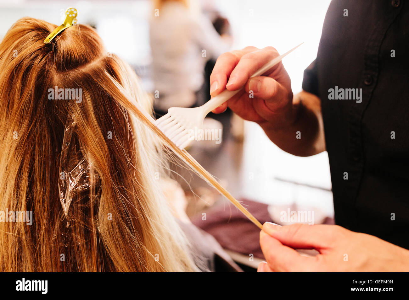 Un capello colorista, un uomo con un pennello per coprire le sezioni di una donna di capelli biondi. Foto Stock