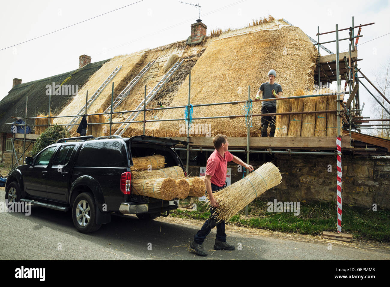 La Thatcher lo scarico di fasci di paglia da un carrello. Foto Stock