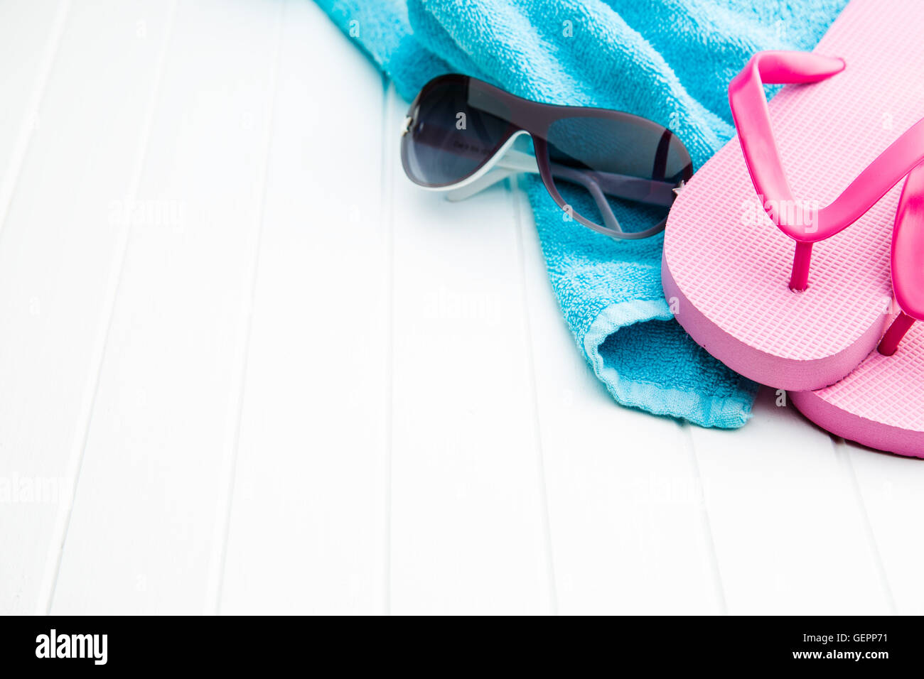 Rosa flip flop con asciugamano e gli occhiali da sole sul pavimento bianco. Foto Stock