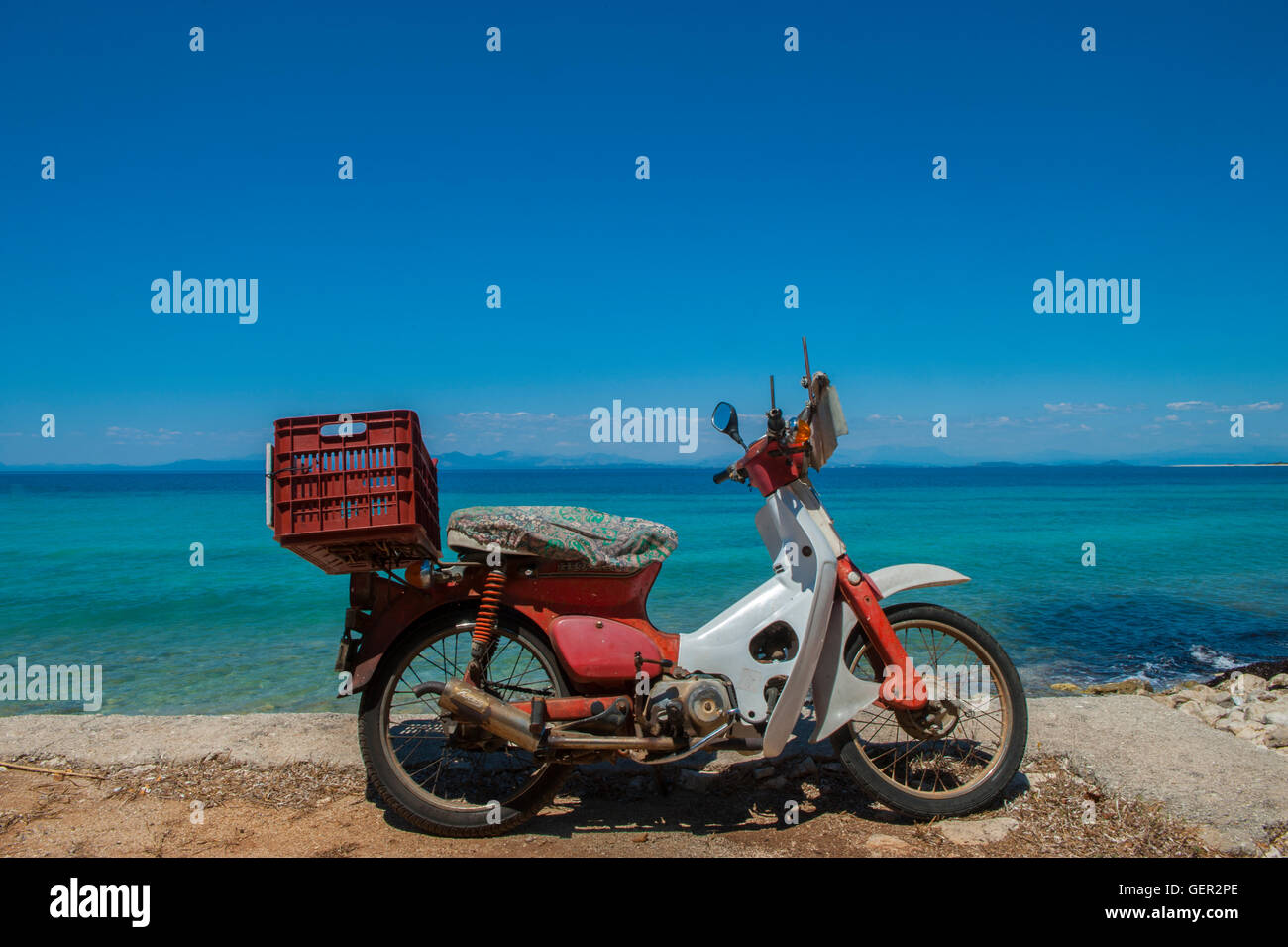 Un solitario, vecchio ciclomotore su una spiaggia deserta in Grecia Foto Stock