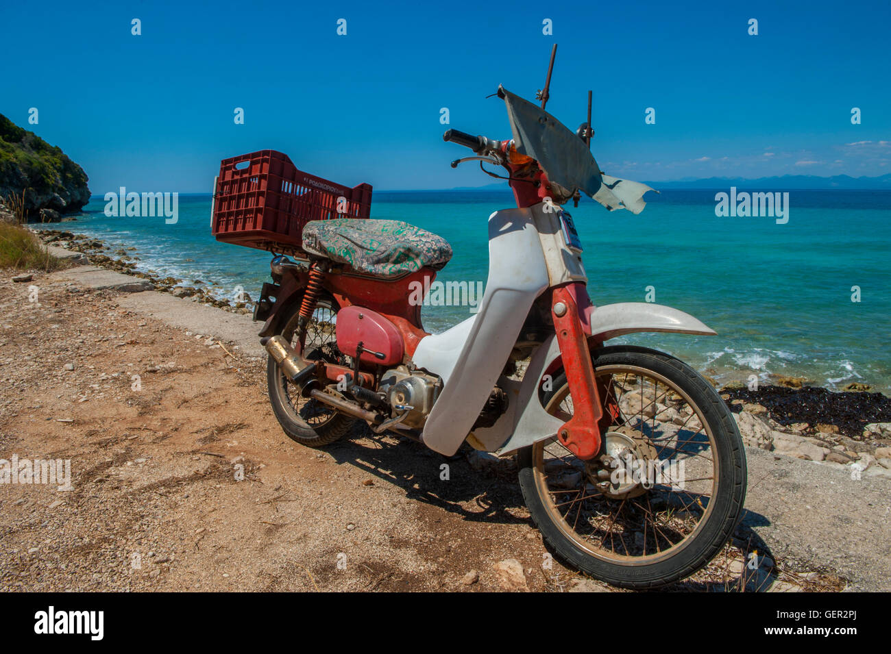Un solitario, vecchio ciclomotore su una spiaggia deserta in Grecia Foto Stock