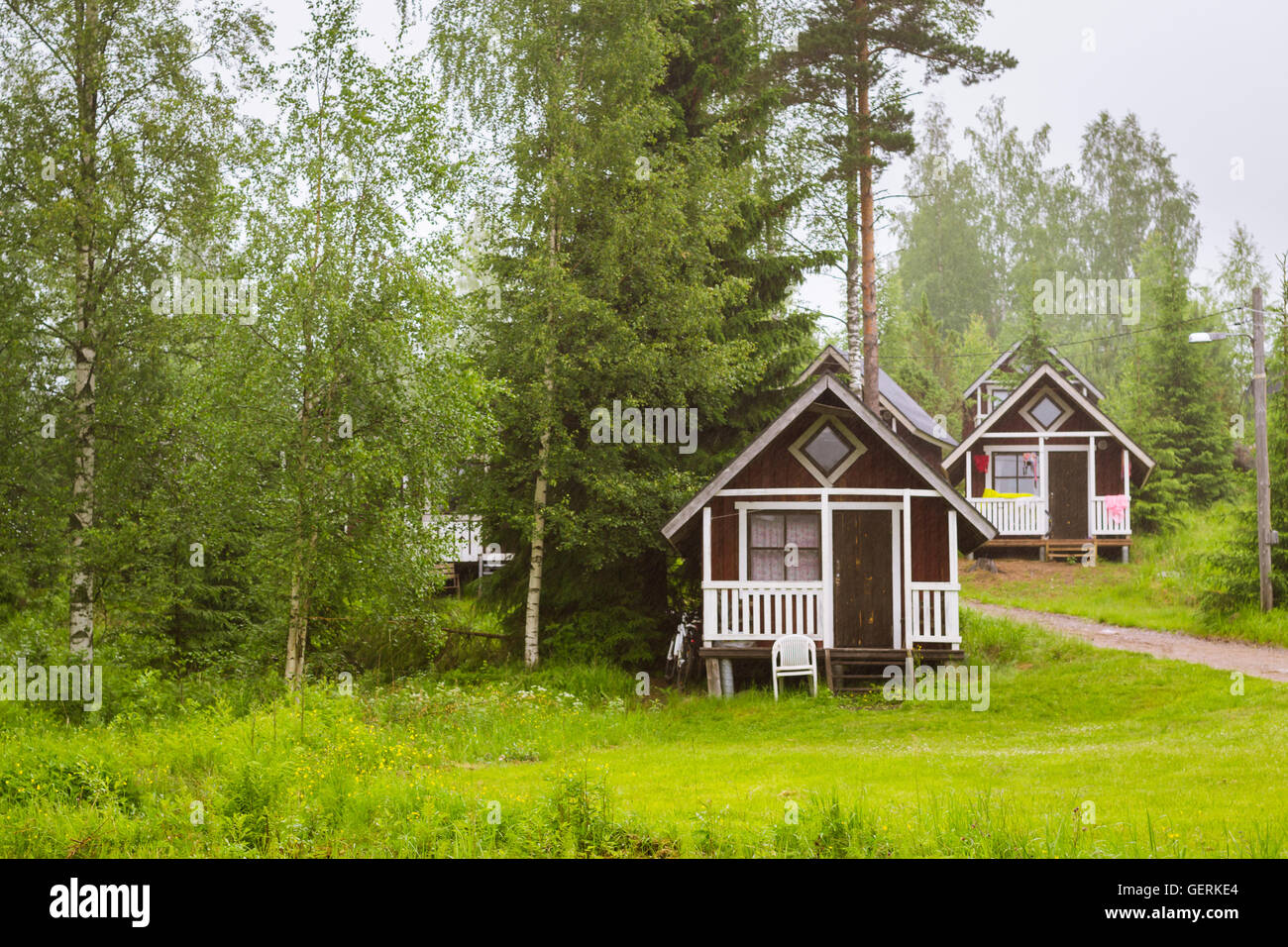 Estate di attività ricreative all'aperto, scandinavo vacanza. Piccolo campeggio in legno case sotto la pioggia di estate su un prato verde. Finlandia Foto Stock