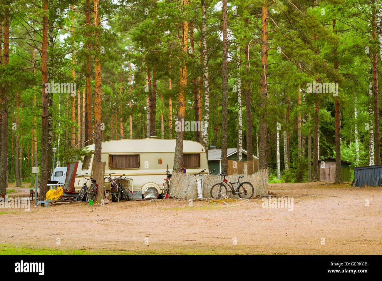 Estate di attività ricreative all'aperto, scandinavo vacanza. Camping furgoni e biciclette parcheggiate in un campeggio boscoso tra alberi di pino. Finlandia Foto Stock