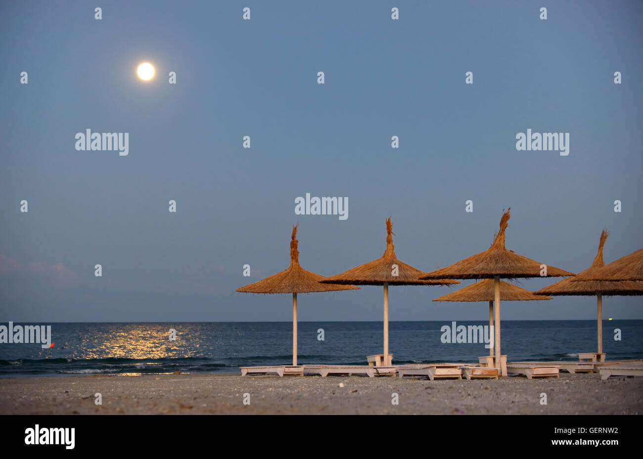 Ombrellone sulla spiaggia e la luna in estate Foto Stock