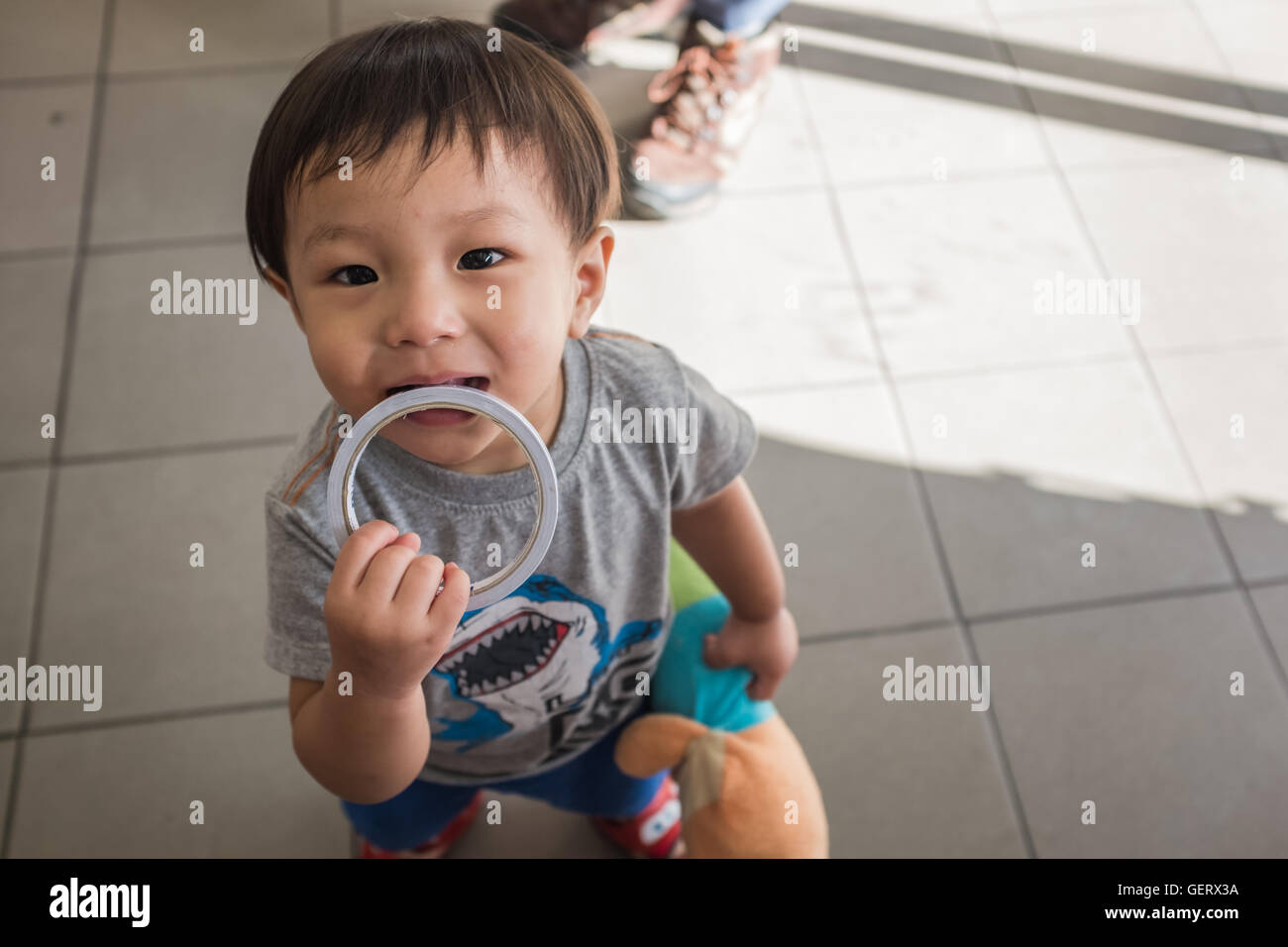 Un giovane bambino mordere anello metallico in negozio,Chiang Mai Thailandia Foto Stock