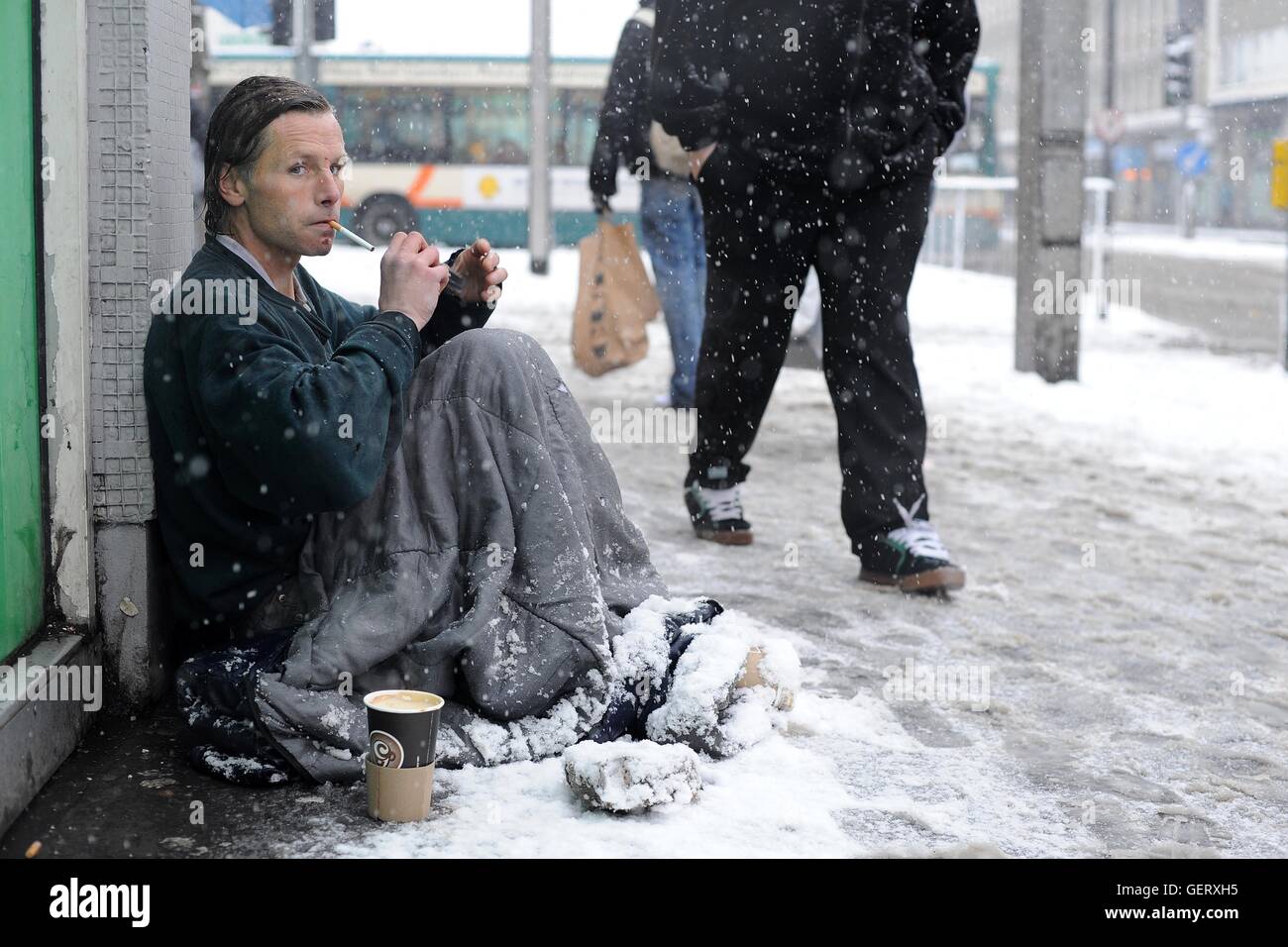 Un senzatetto si siede in una strada nel centro di Cardiff durante la nevicata durante un inverno freddo a Cardiff, nel Galles. Foto Stock