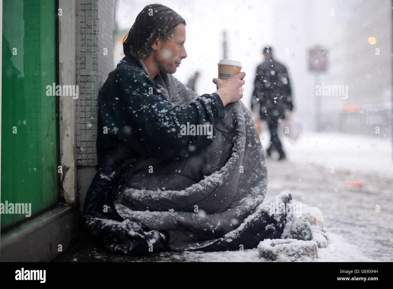 Un senzatetto si siede in una strada nel centro di Cardiff durante la nevicata durante un inverno freddo a Cardiff, nel Galles. Foto Stock