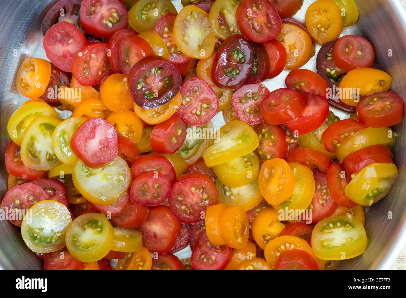Solanum lycopersicum. Mini a fette di pomodoro ciliegino varietà in una padella Foto Stock