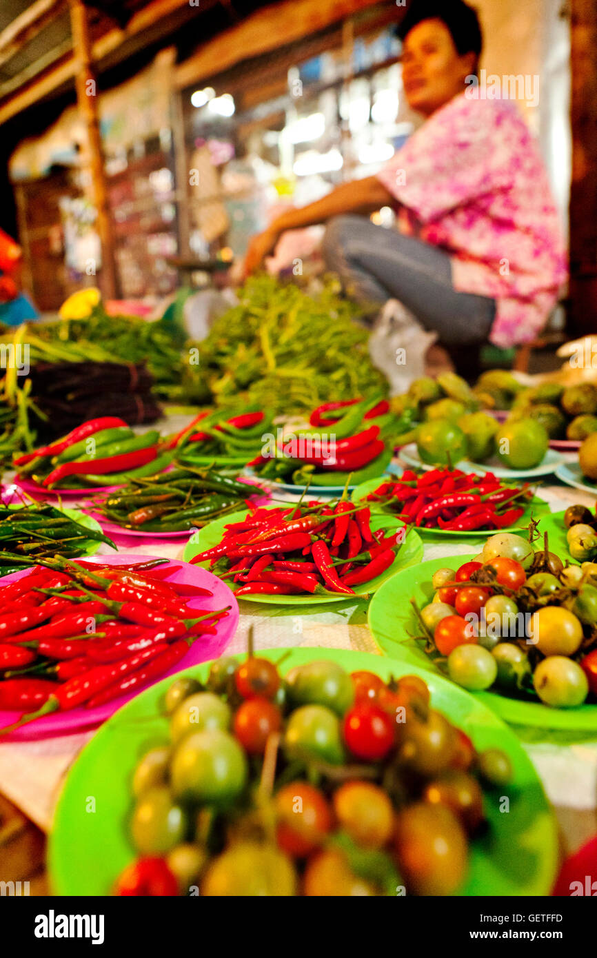 Un mercato thailandese trader con un display di peperoncino fresco e i pomodori in Sukhothai. Foto Stock