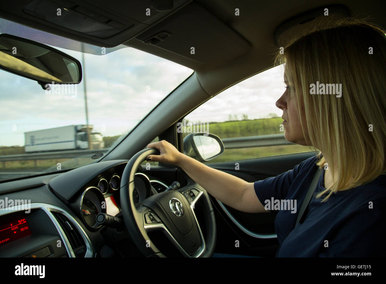 Giovane donna la guida su una strada a doppia carreggiata. Foto Stock