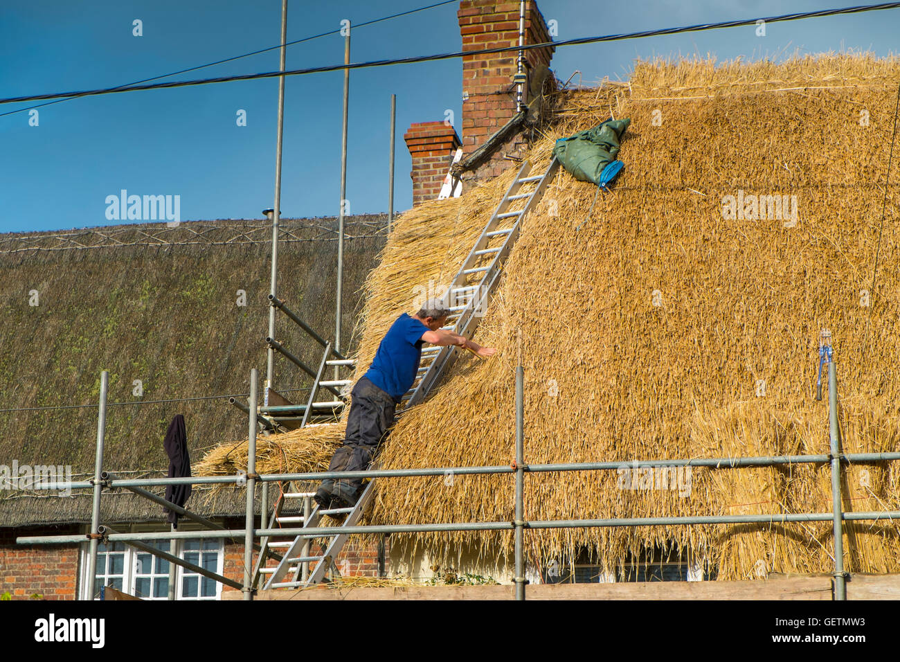 La Thatcher il rifacimento dei tetti con erba di frumento Paglia. Foto Stock