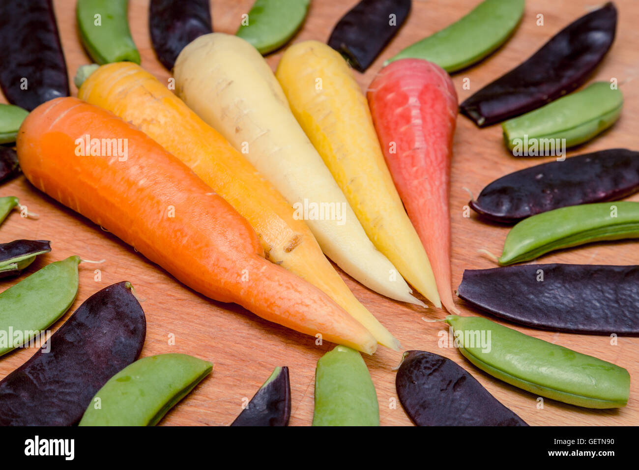 Cinque varietà di colori e di carota circondato da viola taccole e zucchero piselli a scatto Foto Stock