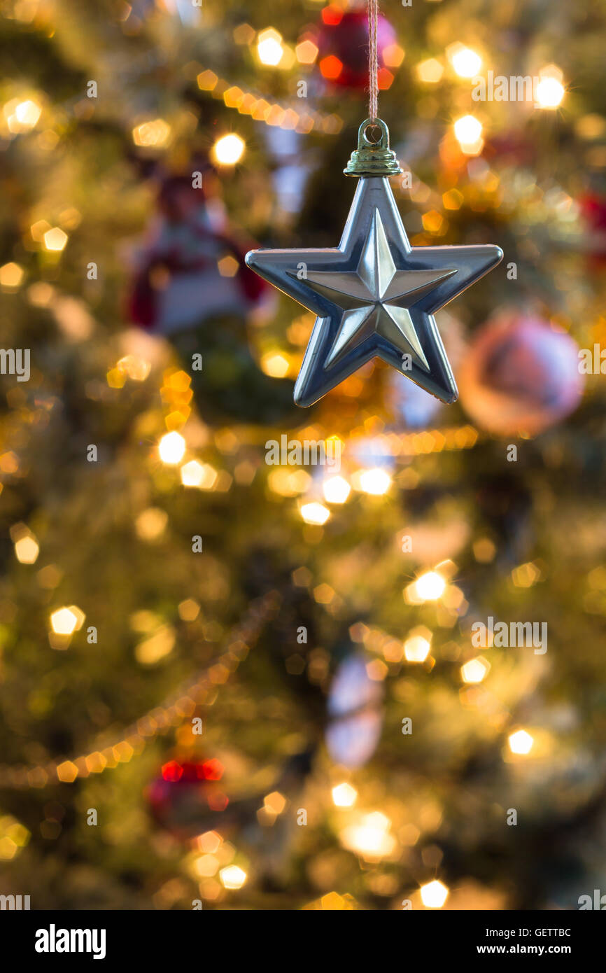 Stella decorativa si blocca nella parte superiore sinistra del colpo verticale con fuori fuoco albero di Natale in background Foto Stock