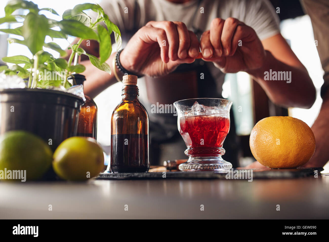 Immagine ravvicinata di barman mani preparare il Negroni cocktail con succo di pompelmo. Egli è di mettere qualche essenza da pelle di pompelmo int Foto Stock