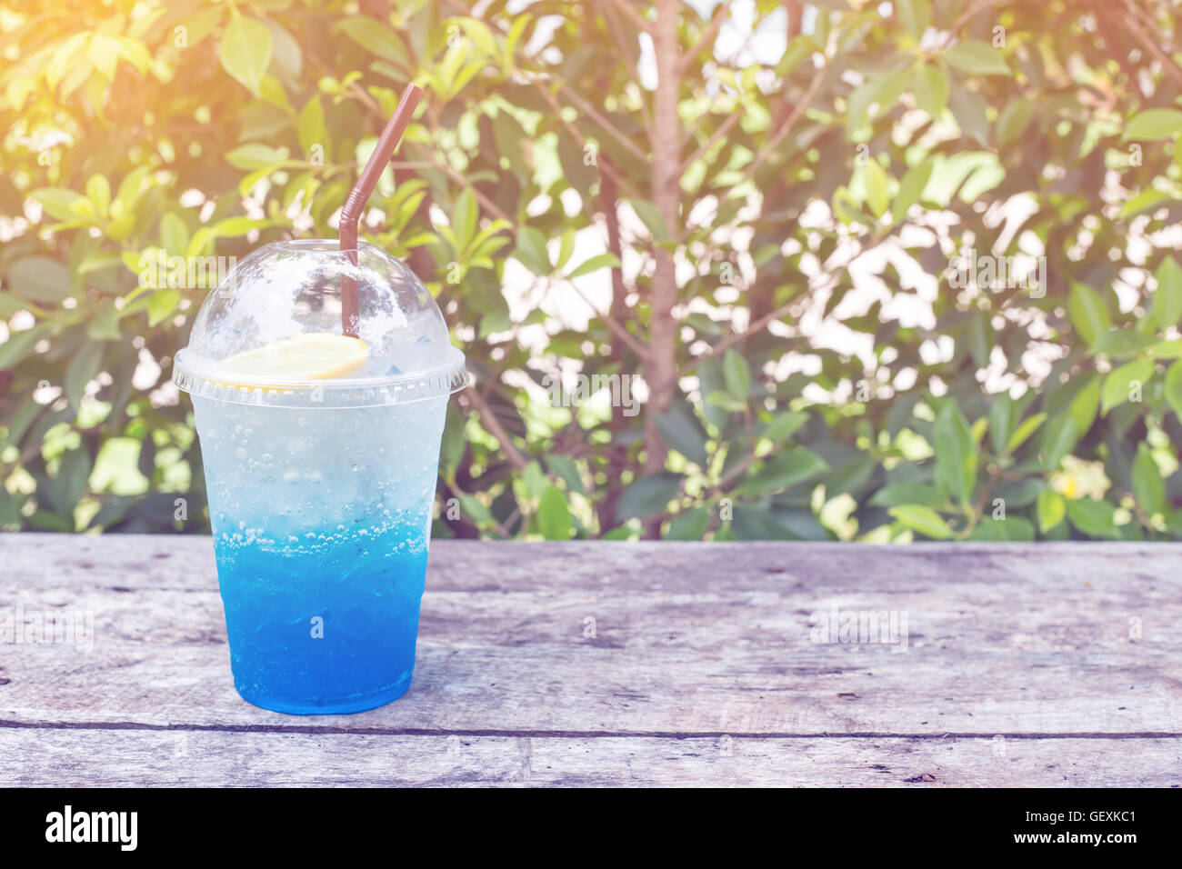 Blu di soda di limone sulla tavola di legno con foglie verdi di sfondo, essere fresco nella natura toni pastello Foto Stock