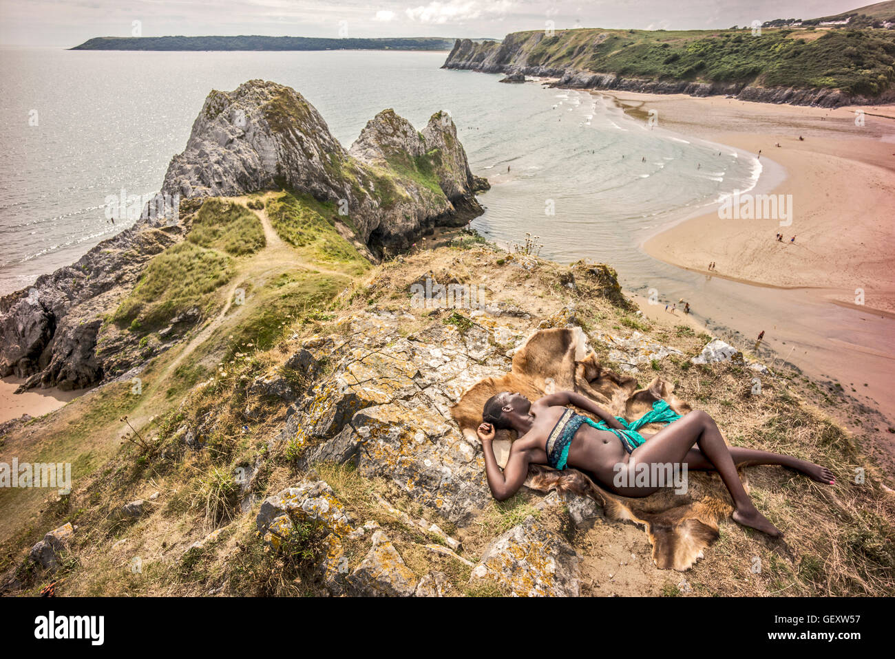 Un afro-caraibica donna relax sulle colline che si affacciano su tre Clffs Bay in Gower. Foto Stock