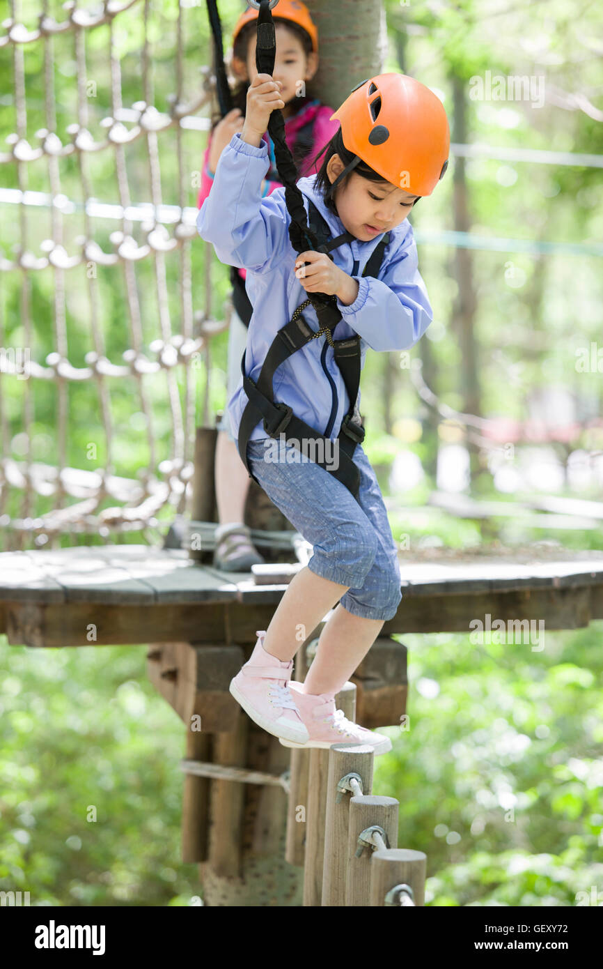 Felici i bambini cinesi in riproduzione in tree top parco avventura Foto Stock