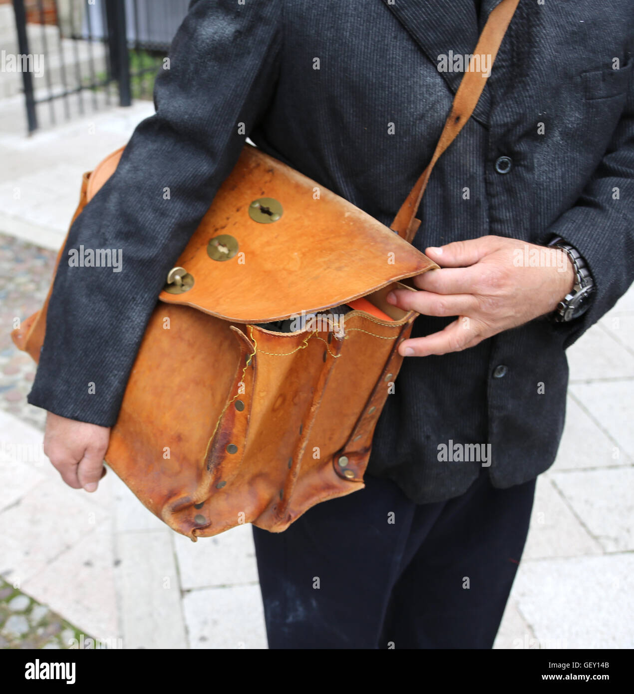 Vecchio postino con la vecchia borsa piena di lettere durante la consegna  di posta nella città Foto stock - Alamy