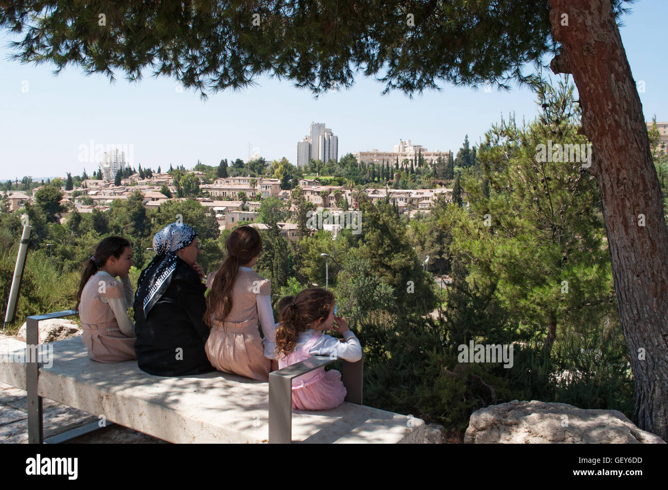 Gerusalemme: una famiglia di ebrei ortodossi seduti all'ombra godendo della vista di Mishkenot Sha'ananim, il primo quartiere ebraico fuori le mura Foto Stock