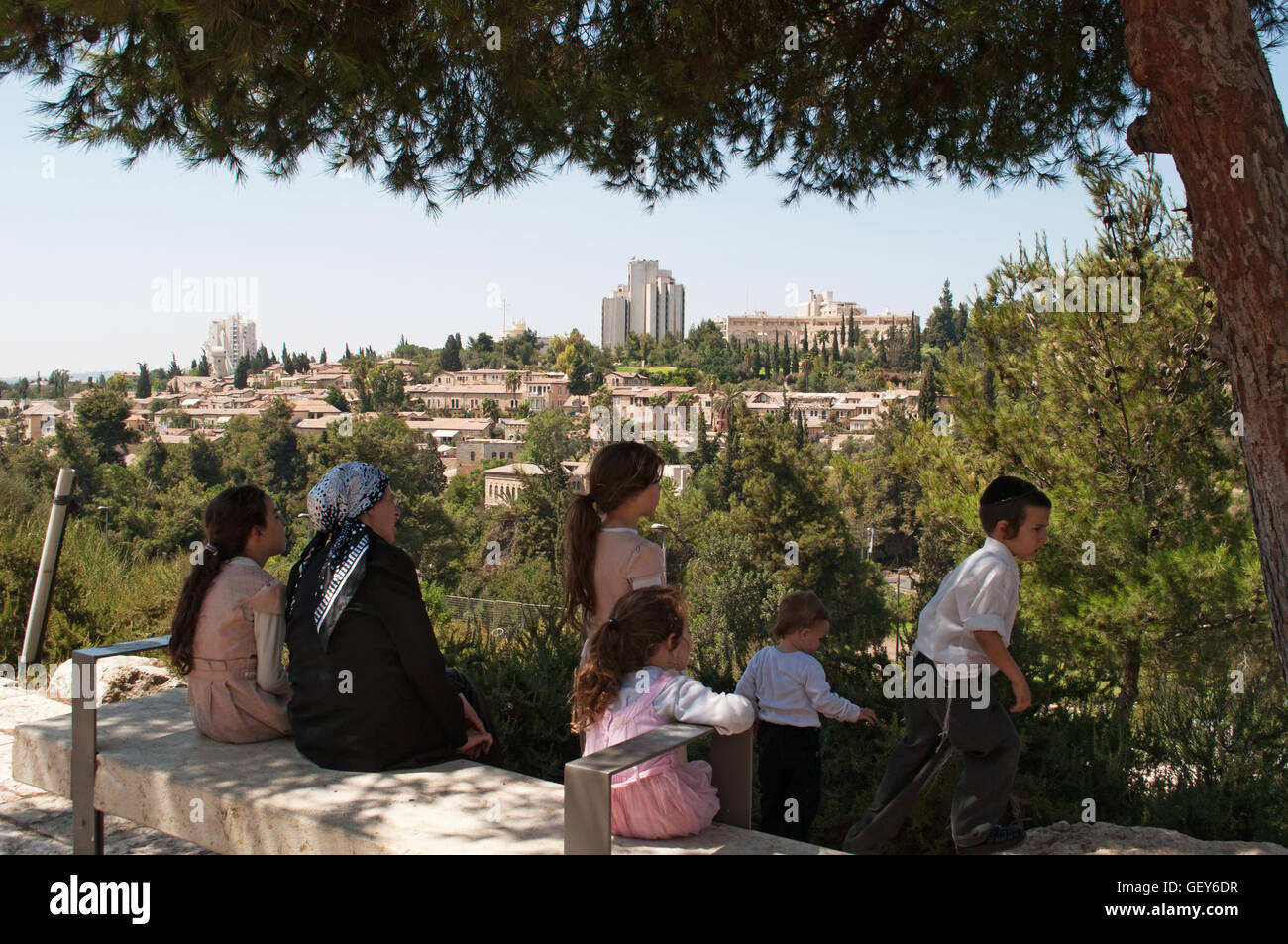 Gerusalemme: una famiglia di ebrei ortodossi seduti all'ombra godendo della vista di Mishkenot Sha'ananim, il primo quartiere ebraico fuori le mura Foto Stock