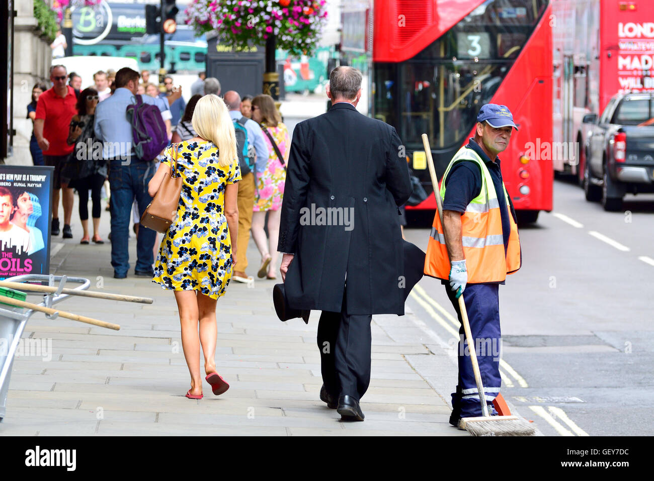 Londra, Inghilterra, Regno Unito. Donna e uomo che porta un cappello a cilindro a camminare lungo una strada il detergente in Whitehall Foto Stock