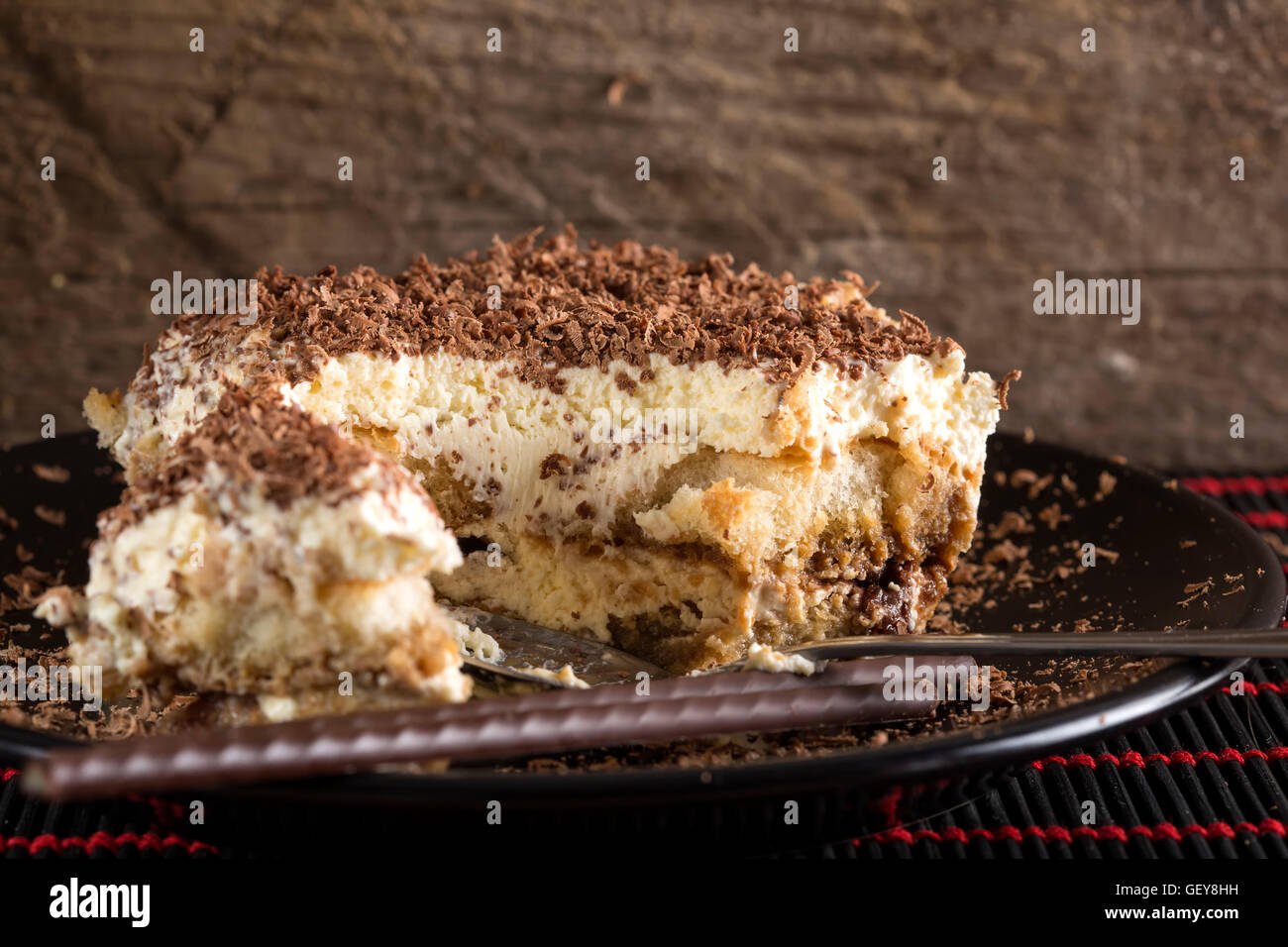 Il tiramisù torta e cucchiaio sulla piastra scuro con sfondo di legno Foto Stock