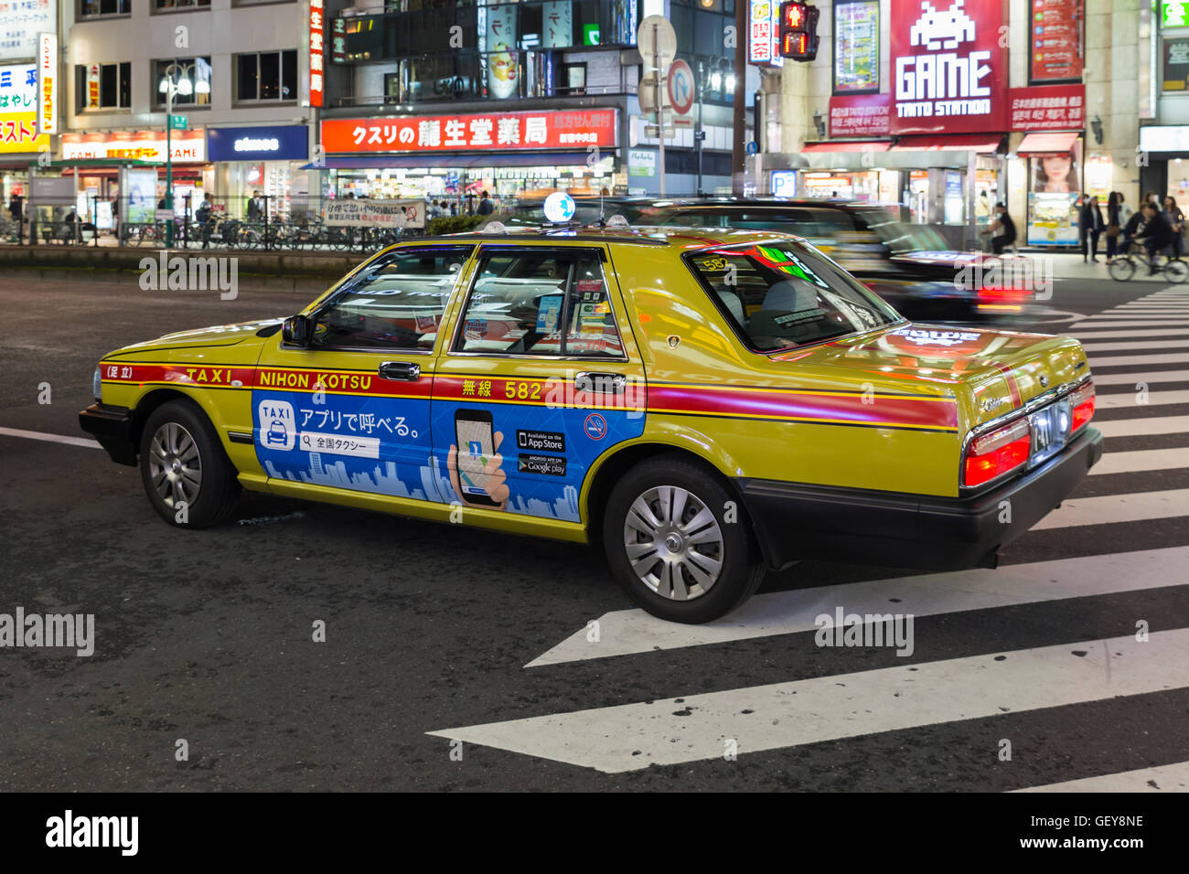 Un taxi giallo in attesa di notte per gli ospiti su una strada trafficata nel quartiere Shinjukunishiguchi a Tokyo Foto Stock