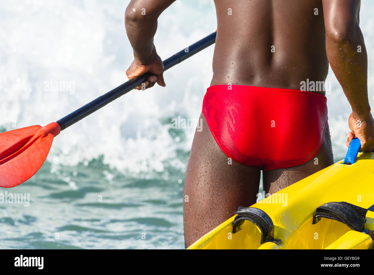 Bagnino paddling giallo rosso mezzo di salvataggio oceano onde Foto Stock