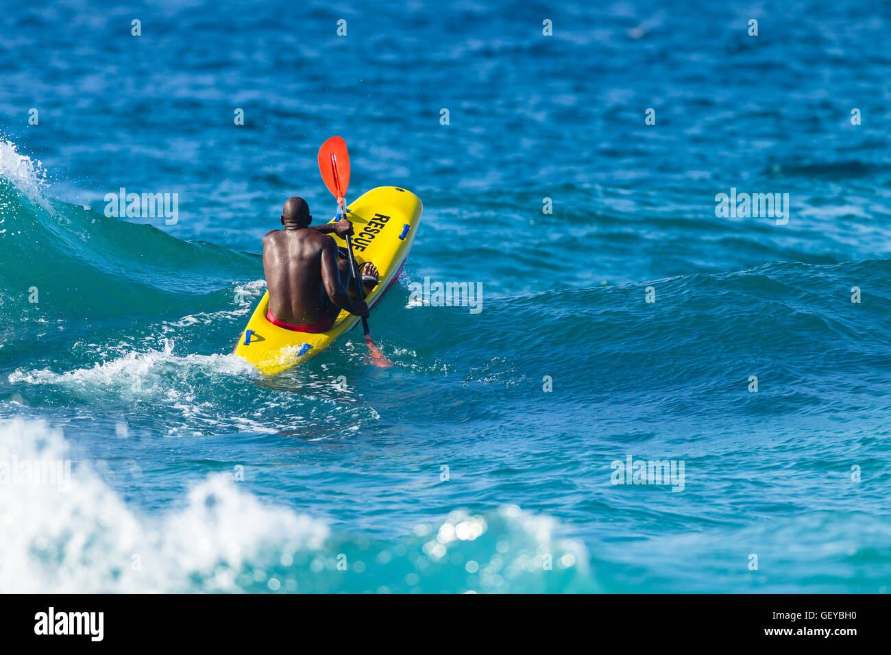 Bagnino paddling giallo rosso mezzo di salvataggio oceano onde Foto Stock