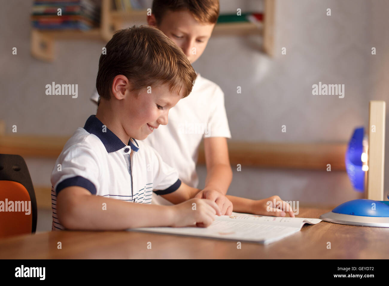 Happy little boy lo studio a casa con il fratello alla scrivania, istruzione Foto Stock