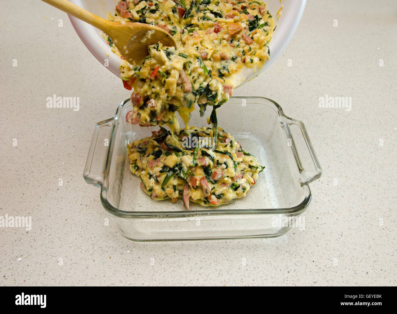 La preparazione del cibo che mostra casseruola miscela che viene versata in un piatto da forno Foto Stock