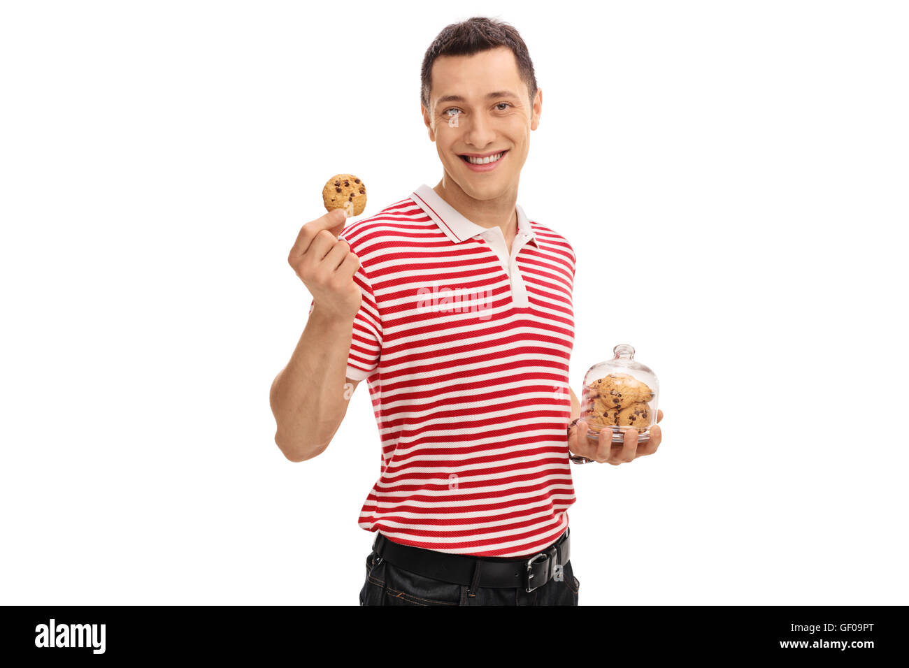 Gioiosa guy tenendo un vaso con i biscotti al cioccolato in una mano e un cookie unico negli altri Foto Stock