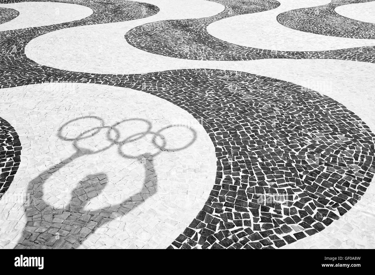 RIO DE JANEIRO, Brasile - 20 Marzo 2015: Ombra di uomo con anelli olimpici sulla piastrella sfondo della spiaggia di Copacabana. Foto Stock