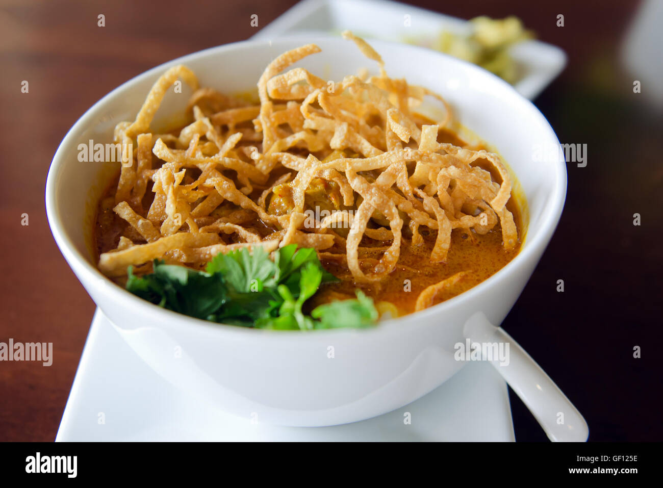 Khao Soi ricetta, Thailandia stile settentrionale salsa speziata zuppa di noodle al pollo con servita con verdure, calce e pasta di peperoncino Foto Stock