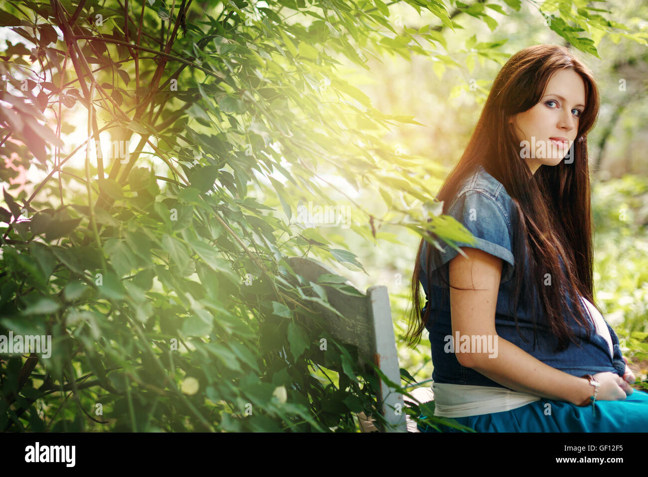 Giovane bella donna aspetta il bambino. La calma atmosfera estiva all'aperto, cercando nella fotocamera. Messa a fuoco selettiva. Spazio per il testo. Foto Stock