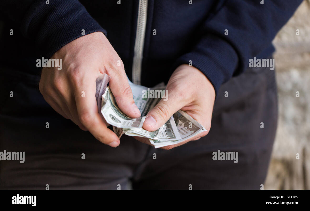 Chiusura del tossicodipendente o spacciatore mani con denaro Foto Stock