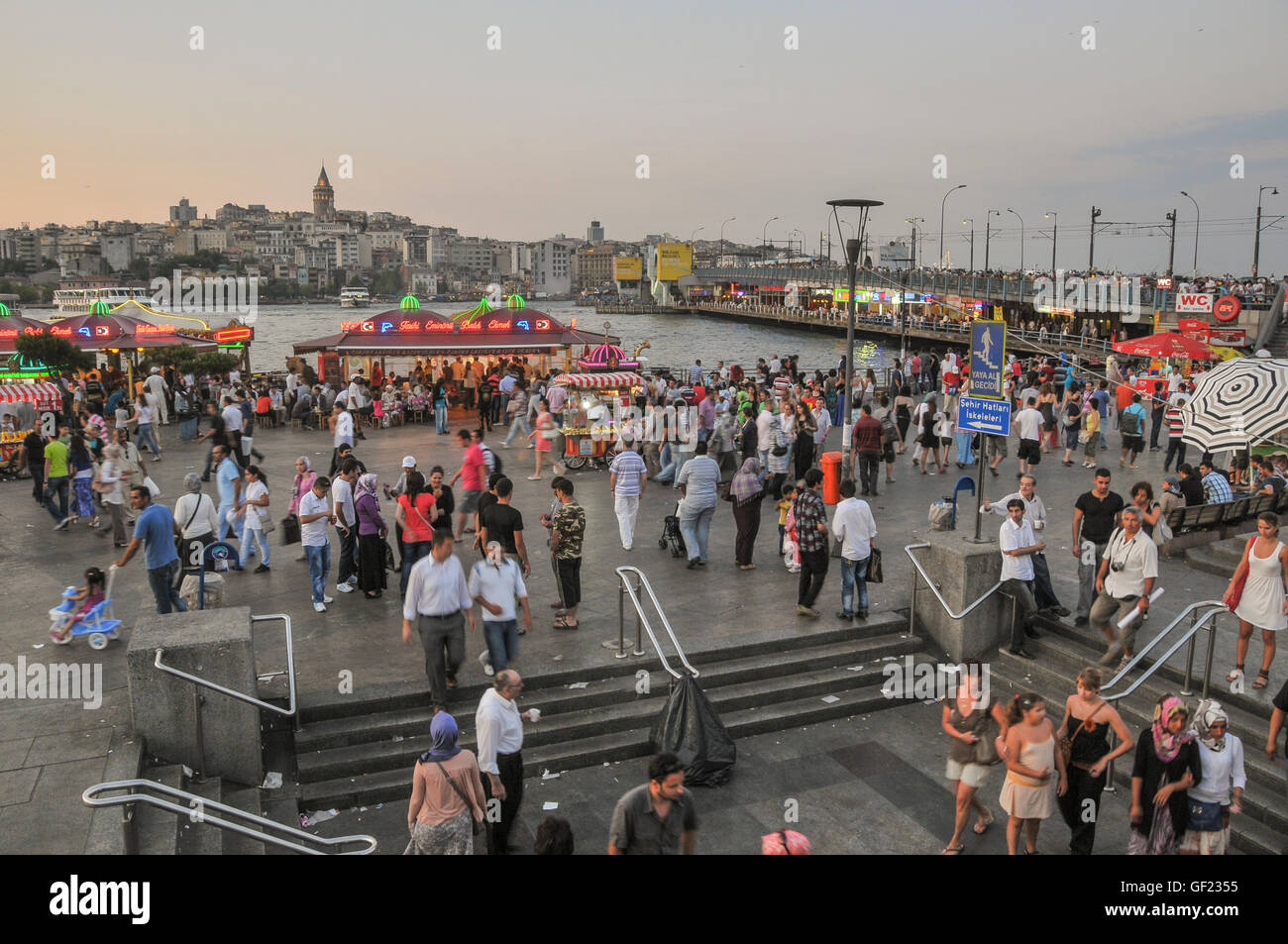 La gente a piedi sul Golden Horn waterfront dal Ponte di Galata in Eminönü in una sera d'estate. Le ringhiere del ponte Galata può Foto Stock