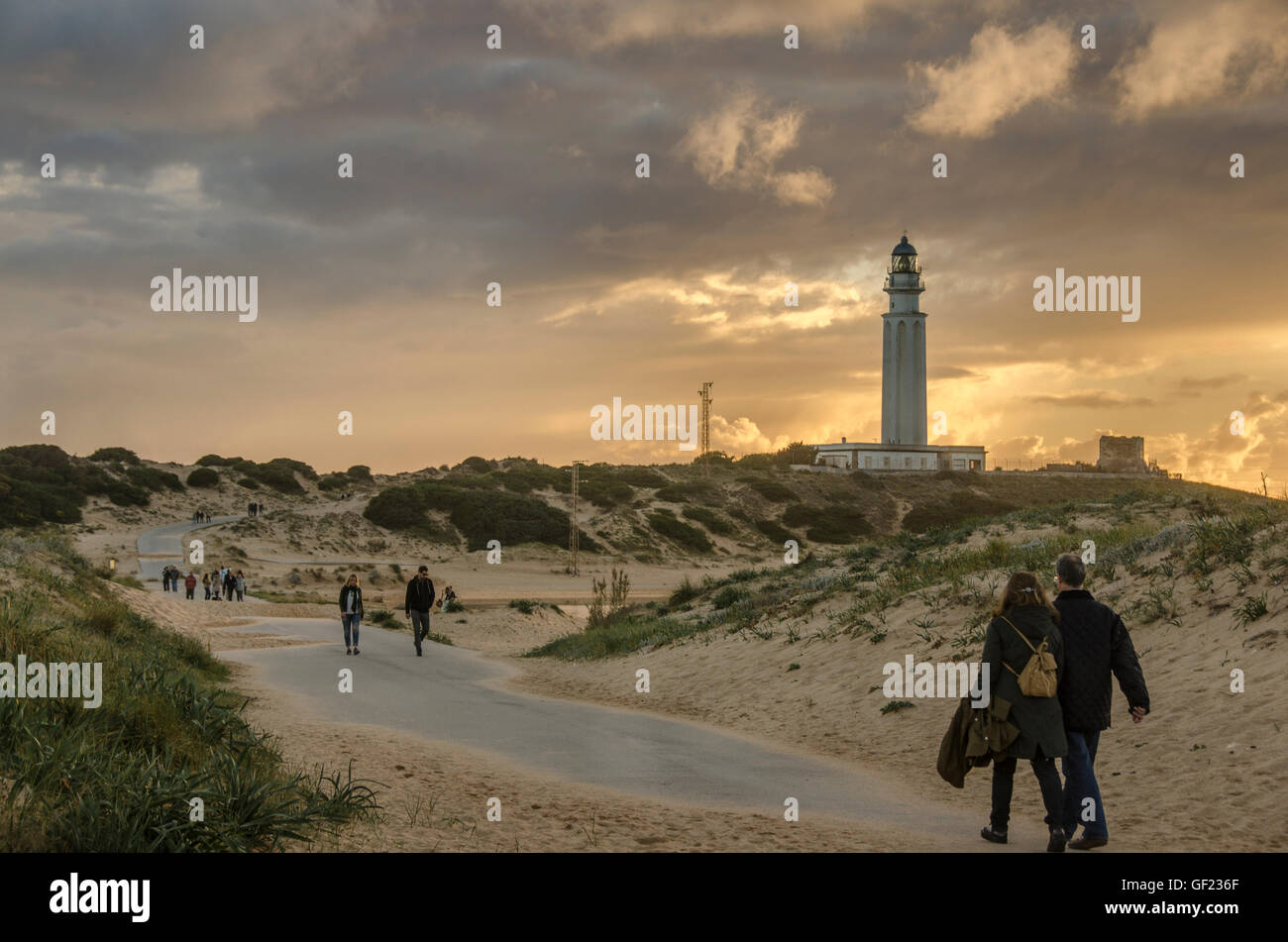 La gente a piedi tra le dune di sabbia verso il faro di Capo Trafalgar, sulla costa dalla piccola località balneare di Los Caños de Foto Stock