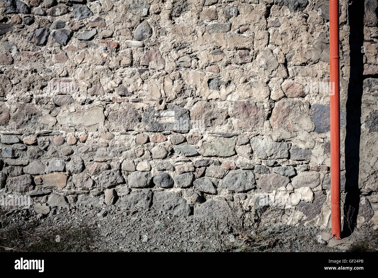 Vecchio weathered muro di pietre e un tubo rosso Foto Stock