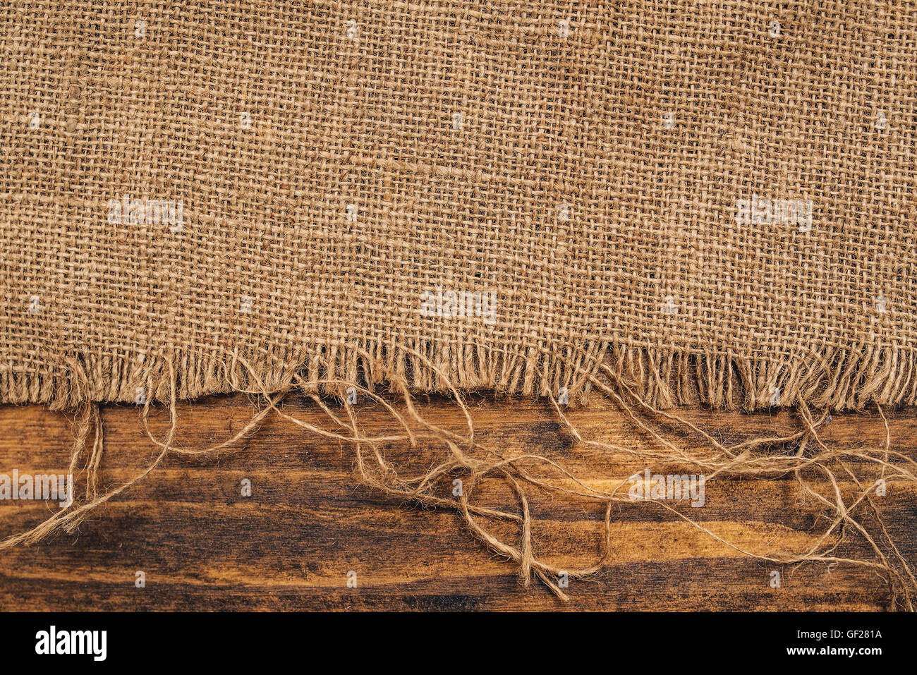 Tela hessian saccheggi su sfondo di legno, rustico sfondo Foto Stock