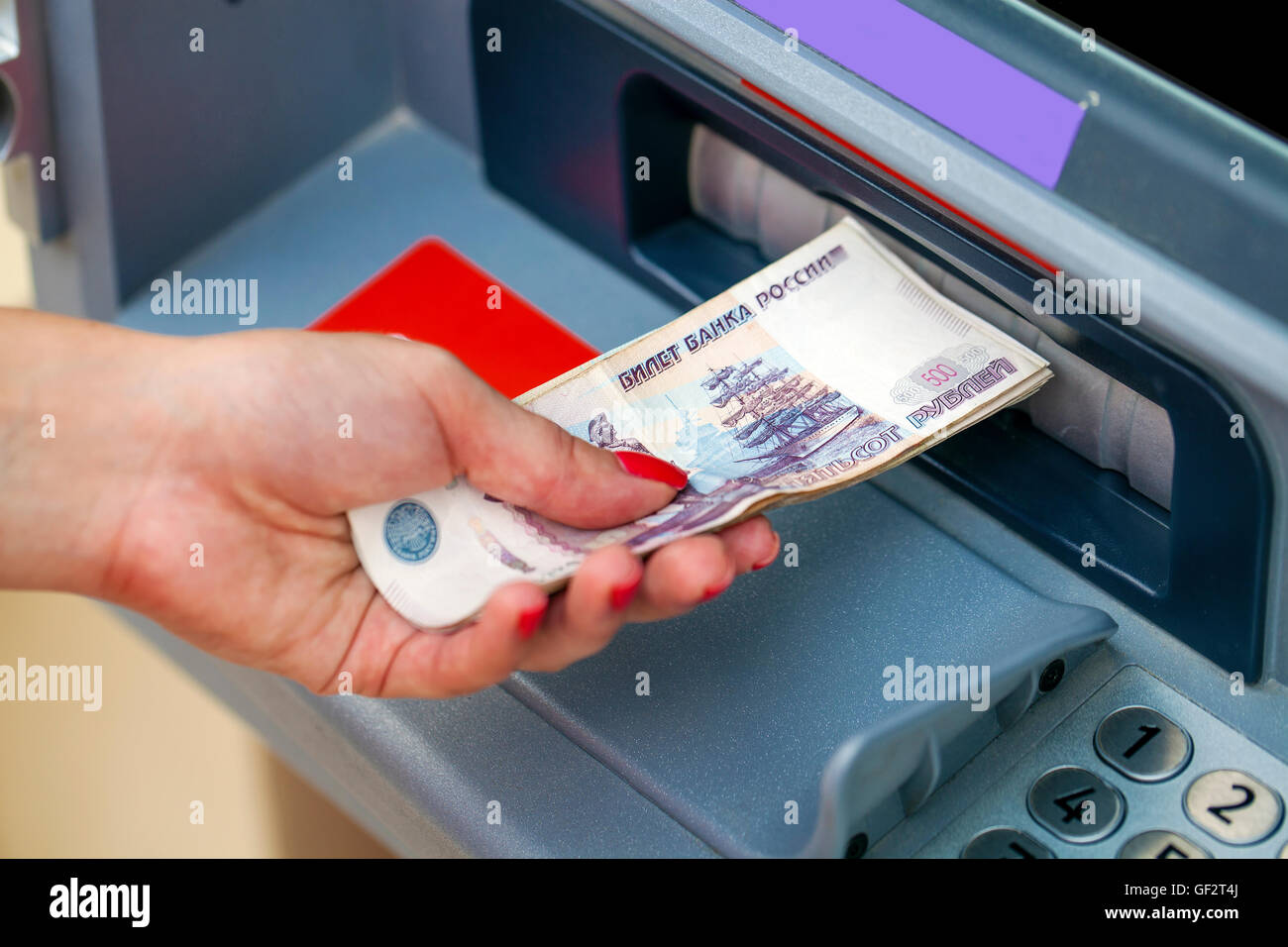 Mani femminili closeup con il russo rubli - donna ritirare il denaro presso sportelli bancomat Foto Stock