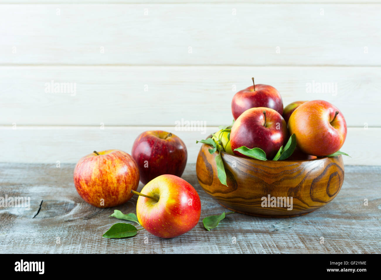 Le mele in ciotola di legno su sfondo rustico. Frutti maturi come cibo vegetariano concetto. Mangiare sano concetto con frutta fresca Foto Stock