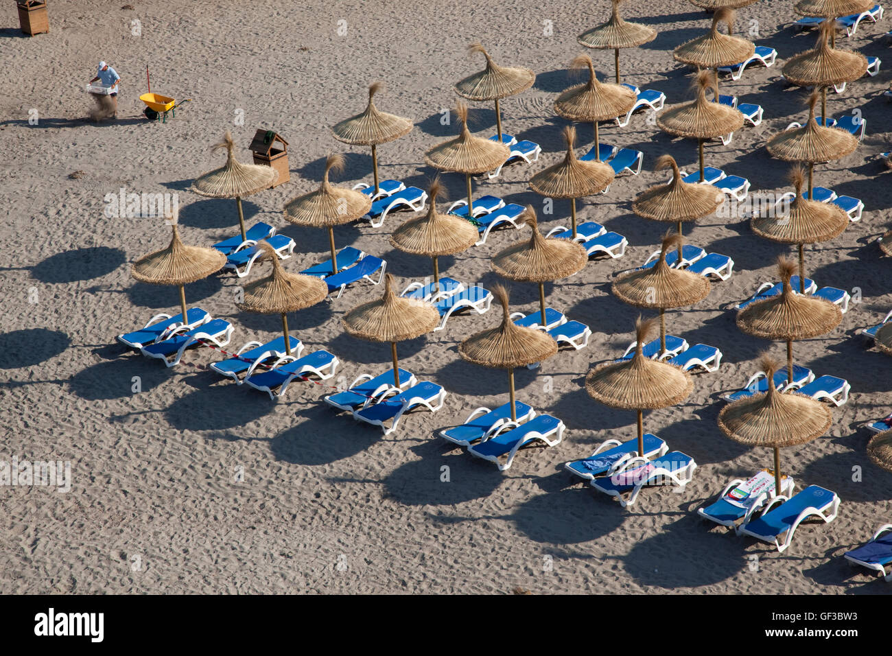 Un uomo che pulisce la spiaggia di mattina presto, prima di arrivare ai bagnanti, in Sant Elm, Mallorca, Spagna Foto Stock